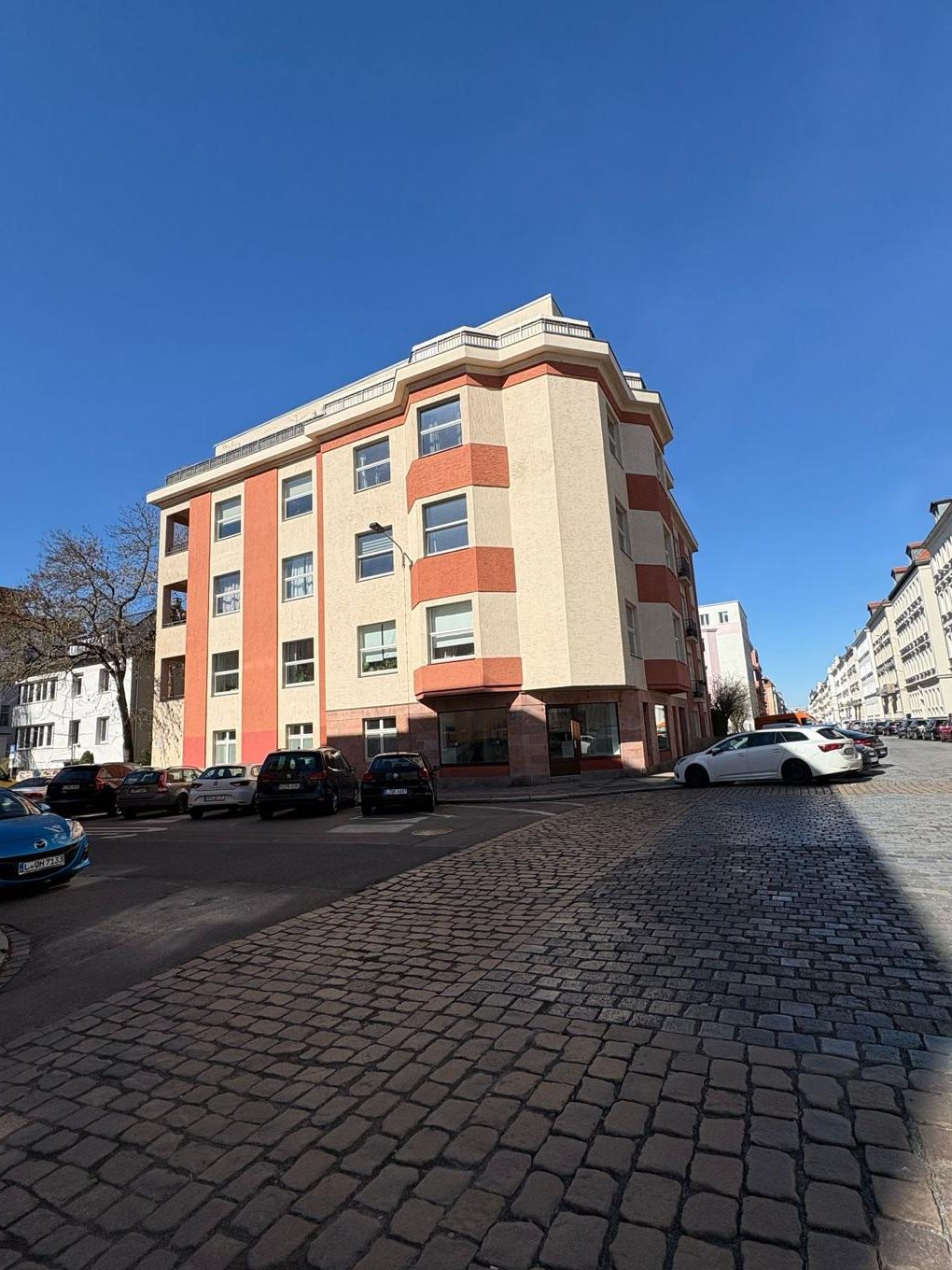 Eckhaus der 1930er-Jahre mit Dachterrasse und roten Fassadenbändern