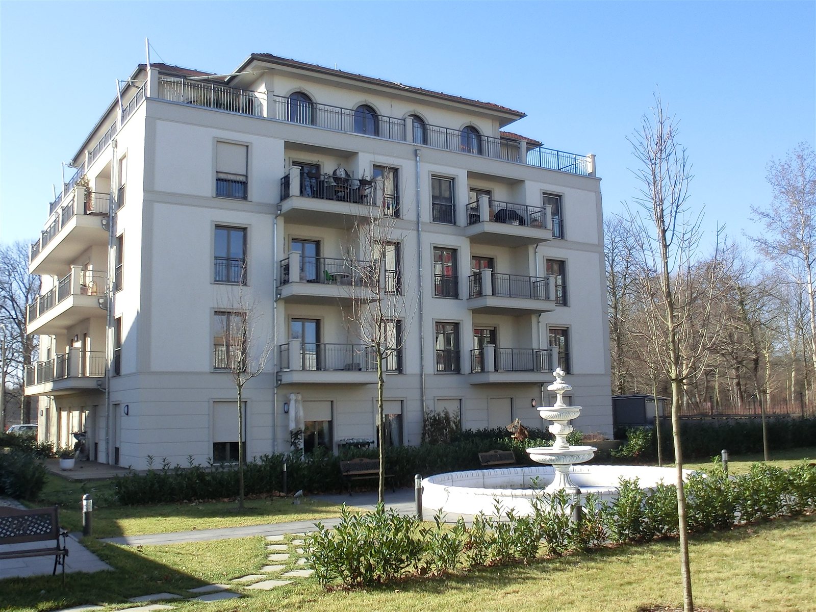 Stadtvilla mit Balkonen und Springbrunnen im Garten