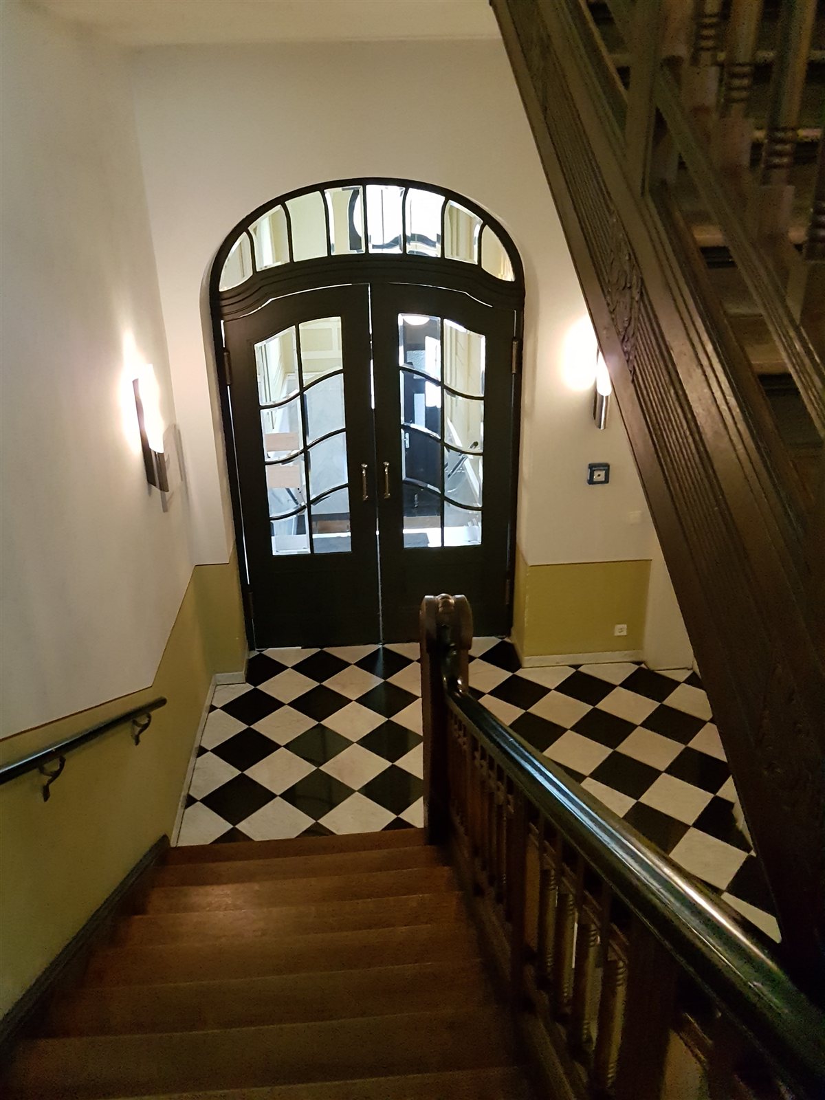 Treppenhaus mit Schachbrettboden und Portaltür
