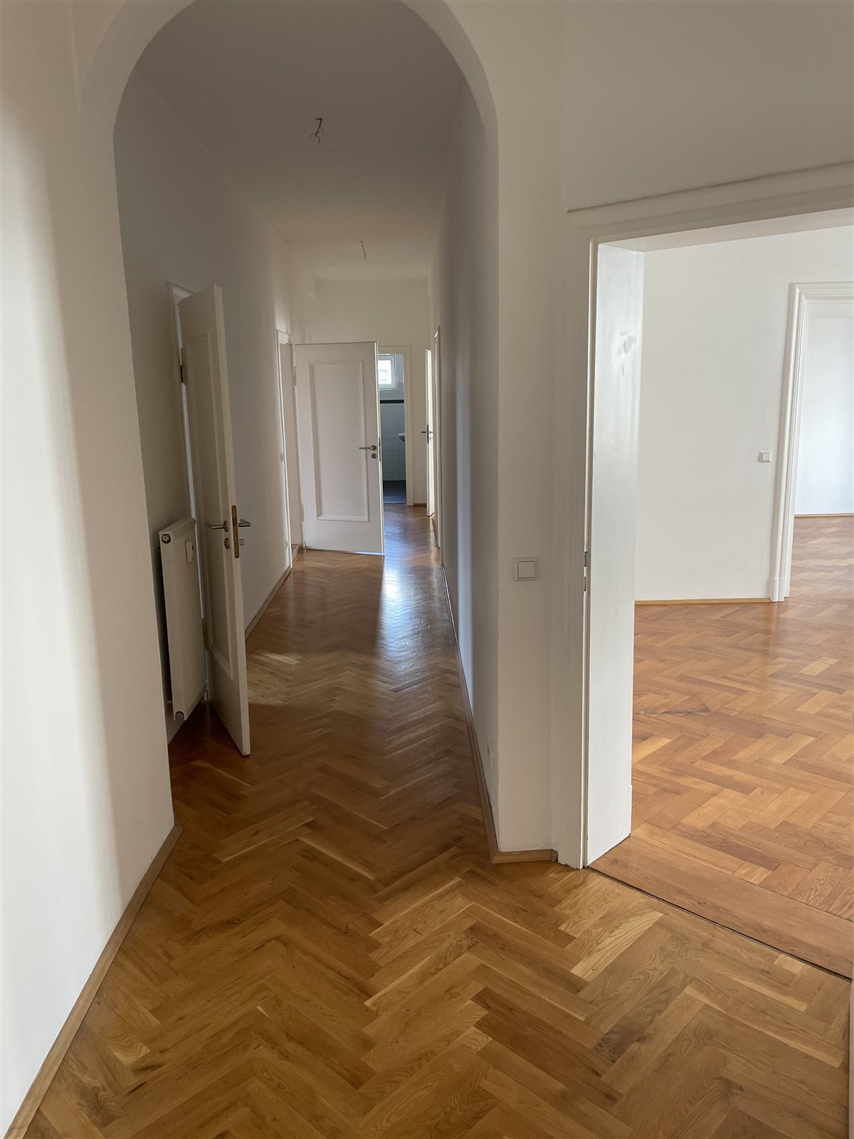Altbauflur mit Rundbögen und Fischgrätparkett