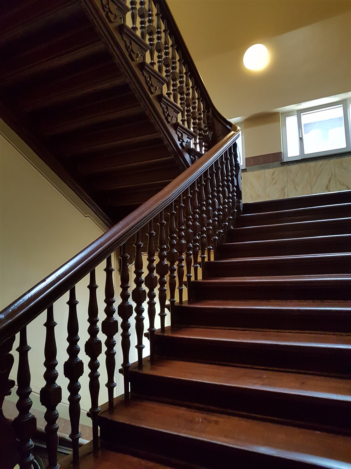 Treppenhaus mit dunklem Holzgeländer