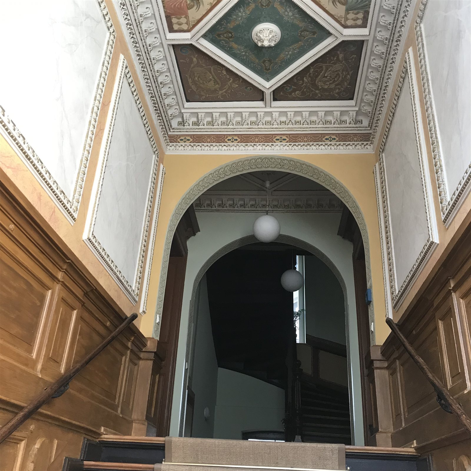 Treppenhaus mit bemalter Kassettendecke und Rundbogen
